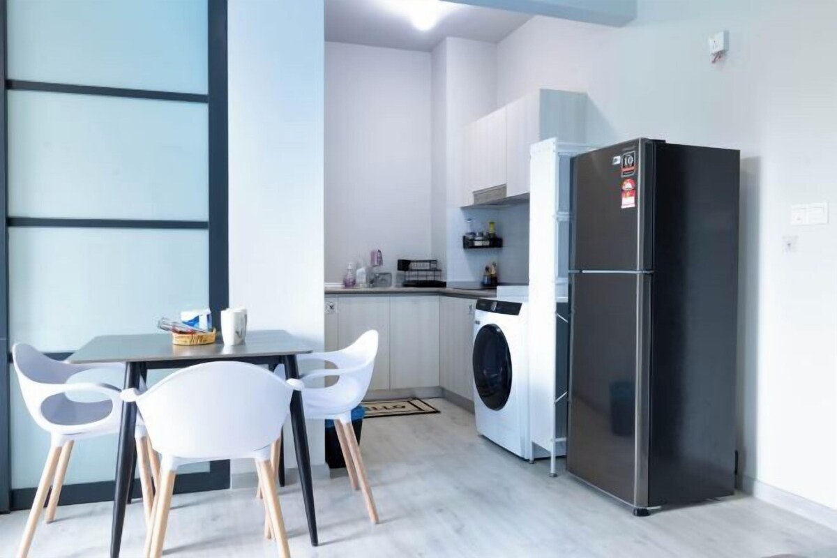 Cocina compacta con lavadora, refrigerador y comedor con sillas.