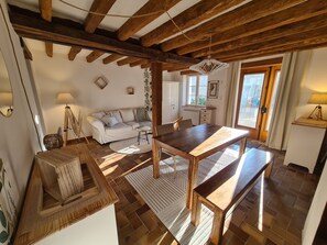 Un intérieur rustique avec des poutres apparentes, une table à manger en bois, un canapé et une fenêtre offrant une vue agréable.