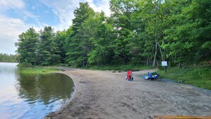 Ein sandiger Strand mit einem Holztisch und einem Kanu.