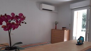 A room with a wooden desk, a potted orchid, a dresser, and a small table with a decorative item. - Apartment for 4, air-conditioned 4, Terrace 15 m² - beach, town center on foot (Mandelieu-la-Napoule)