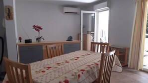 A dining area with a table set for four, a wooden cabinet, and a potted plant. - Apartment for 4, air-conditioned 4, Terrace 15 m² - beach, town center on foot (Mandelieu-la-Napoule)