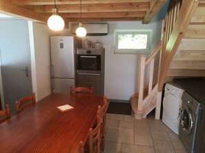 Une cuisine avec une table en bois, des chaises, un lave-linge et un four encastré.
