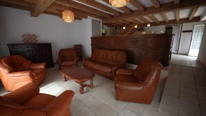Un ampio soggiorno con mobili in pelle, travi in legno e una cucina sullo sfondo.