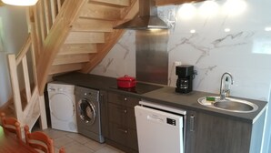 Una cucina compatta con lavatrice, lavastoviglie e macchina da caffè.