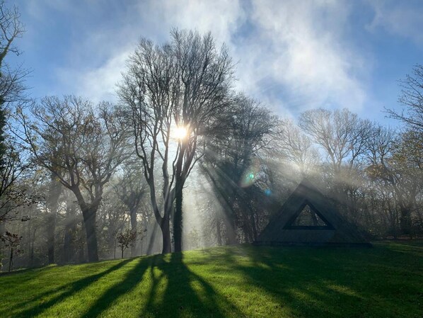 A serene park with a clear sky, a grassy area, and a triangular structure.