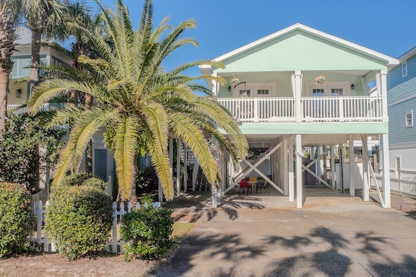 Open underneath and an airy deck with flowing curtains and swinging chair are seen. Even more goodies upstairs! Just 1 block from the beautiful white-sand beach and the Gulf of Mexico.