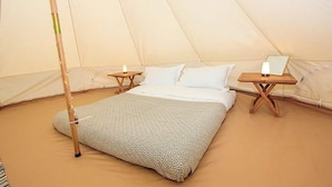 A tent with a bed, two bedside tables, and a lamp on each table. - 11 'bellatrix' Bell Tent Glamping Anglesey (Holyhead)