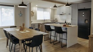 Een moderne keuken met een houten eettafel, zwarte stoelen en hanglampen.