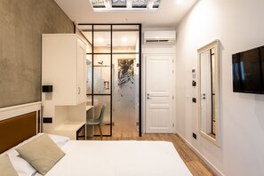 Ein modernes Hotelzimmer mit Bett, Schreibtisch, Stuhl und Fernseher.