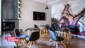 Un espace de détente moderne avec une cheminée, des sièges confortables et une grande fresque murale.