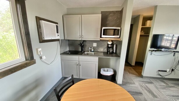 Una cocina compacta con una mesa de comedor, un microondas y un televisor.