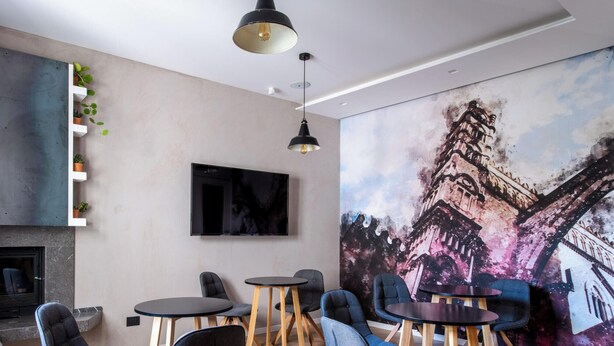 Un espace de travail moderne doté d’une cheminée, de plusieurs coins salon et d’une grande fresque représentant un paysage urbain.
