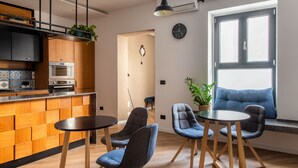 Une cuisine moderne dotée d’appareils électroménagers intégrés, un coin repas avec deux tables et des chaises, et une grande fenêtre offrant une vue dégagée.