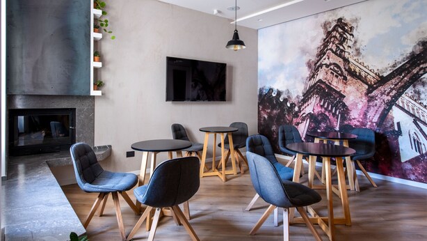 Eine moderne Lounge mit Kamin, bequemen Sitzgelegenheiten und einer großflächigen Stadtkulissen-Mural.