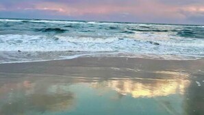 Una platja amb onades i un cel serè.