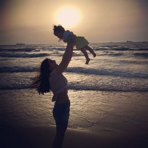 A sunset over the ocean with a person holding a child.