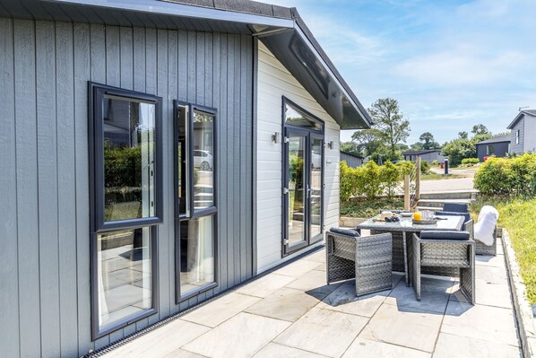 Ein modernes Haus mit großen Fenstern und einer Terrasse mit Gartenmöbeln.