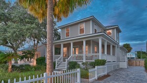 A two-story house with a porch, white picket fence, and a paved driveway. - Private Pool ~ Screened Porch ~ Pet Friendly (Destin)