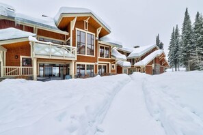 Un gran lodge de madera con varios balcones y amplias ventanas, rodeado de árboles cubiertos de nieve.