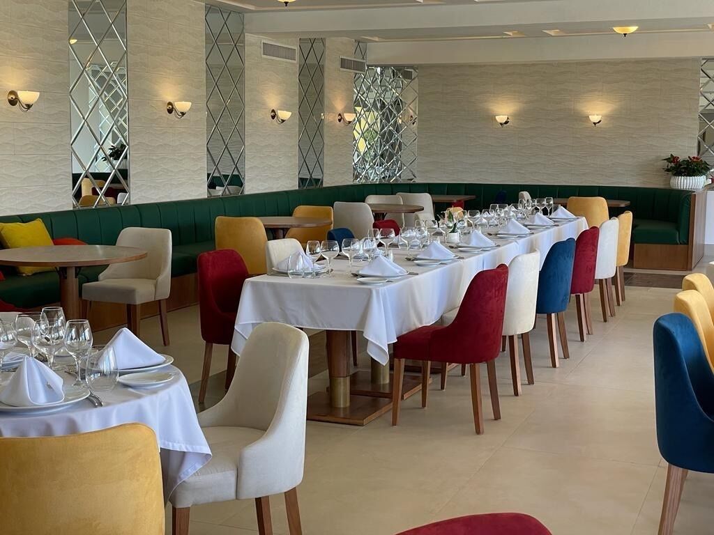 Un restaurante con varias mesas dispuestas para comer, con una variedad de colores de sillas y un diseño interior moderno.