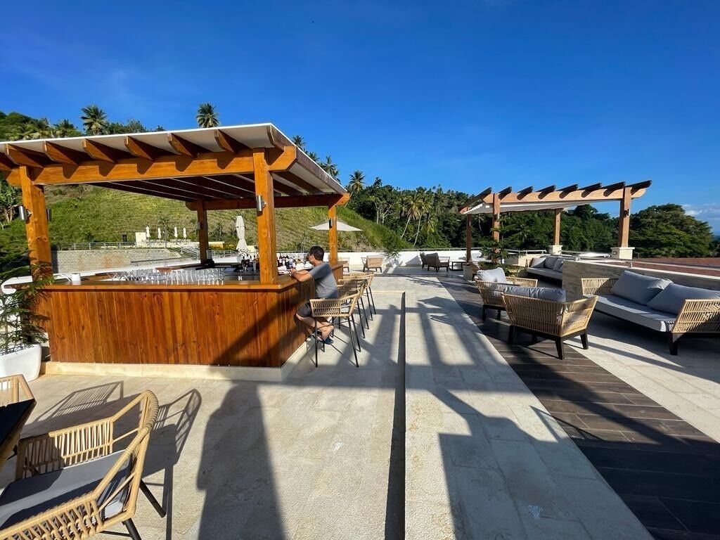 An outdoor seating area with wooden pergolas, wicker furniture, and a bar counter.