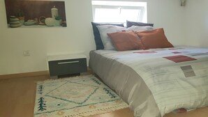 Ein Schlafzimmer mit Bett, Kissen, Teppich, Nachttisch und Wandbild.