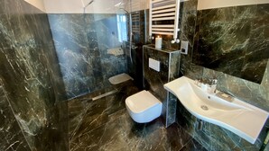 A modern bathroom with a glass-enclosed shower, a white toilet, and a vanity with a sink. - Hotel Amber Port (Darlowo)