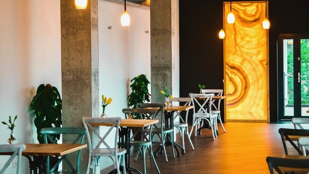 A modern interior with exposed concrete pillars, wooden tables, and hanging pendant lights. - Hotel Amber Port (Darlowo)