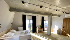 A modern hotel room with a large bed, a desk, and a view of the outdoors. - Hotel Amber Port (Darlowo)