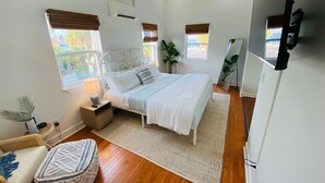 A bedroom with a bed, bedside tables, a mirror, and a TV.