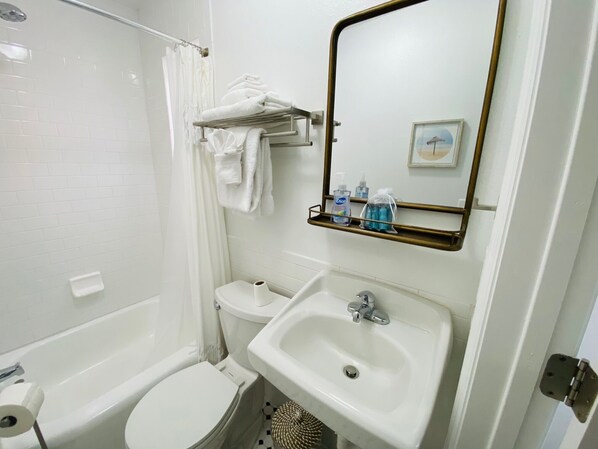 A bathroom with a bathtub, toilet, sink, and a towel rack with towels.