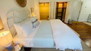 A neatly arranged bedroom with a bed, bedside tables, and a door leading to another room.