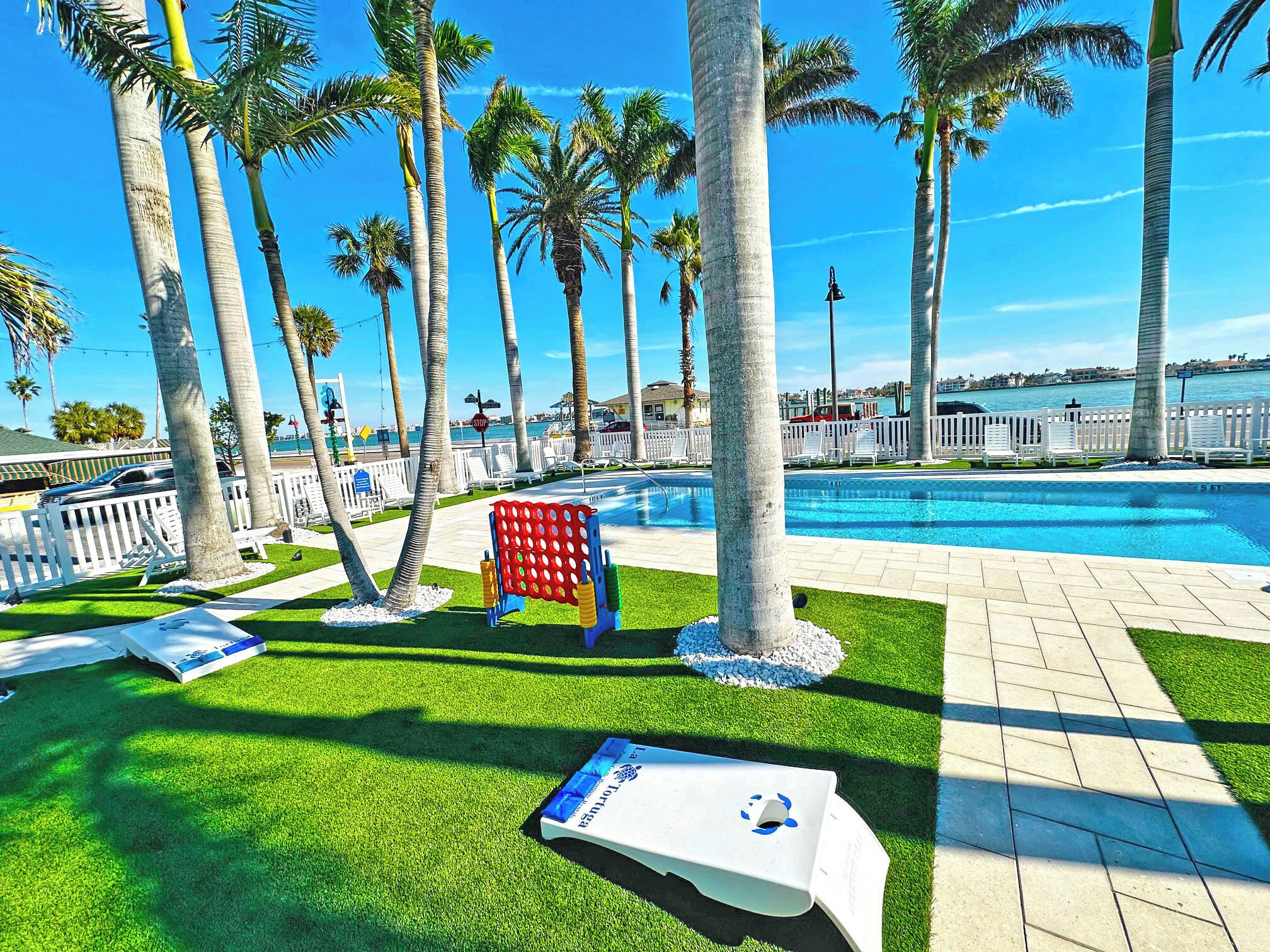 A poolside area with palm trees, a stop sign, and a view of the ocean.