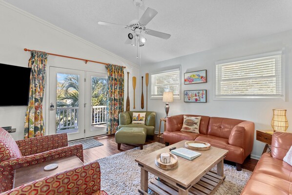 A living room with a sofa, armchair, coffee table, and a television. - Happy Honu - Dog-Friendly Beach Retreat, Screened Porch, Walk to Beach (Kure Beach)