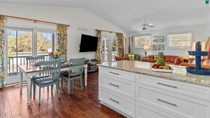 A spacious kitchen with a large island, white cabinetry, and a view of the outdoors. - Happy Honu - Dog-Friendly Beach Retreat, Screened Porch, Walk to Beach (Kure Beach)