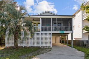 A two-story building with a covered porch and a sign indicating it is a hotel. - Happy Honu - Dog-Friendly Beach Retreat, Screened Porch, Walk to Beach (Kure Beach)