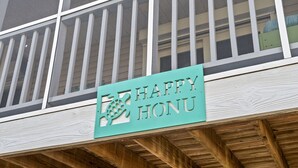 A sign with the text "HAPPY HONU" on a wooden structure. - Happy Honu - Dog-Friendly Beach Retreat, Screened Porch, Walk to Beach (Kure Beach)