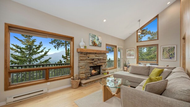 A spacious living room with large windows, a stone fireplace, and a comfortable seating area.