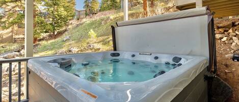 A hot tub with a clear view of the surrounding landscape, including trees and a building in the background.