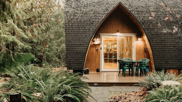 A cozy cabin with a sloped roof, a wooden deck, and a glass door entrance. - 78mbr - Wood Stove - Wifi - Pets Ok - Bbq - Sleeps 6 1 Bedroom Home by RedAwning (Deming)