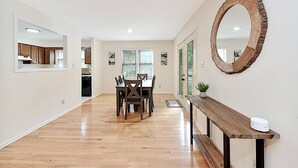 A spacious kitchen with wooden cabinets, a dining area with a wooden table and chairs, and a large mirror on the wall. - Lake Gaston Duo Side B Kayak, Water mat, Gameroom (Bracey)