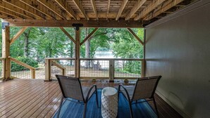 A covered outdoor seating area with wooden beams, a view of trees, and a metal railing. - Lake Gaston Duo Side B Kayak, Water mat, Gameroom (Bracey)