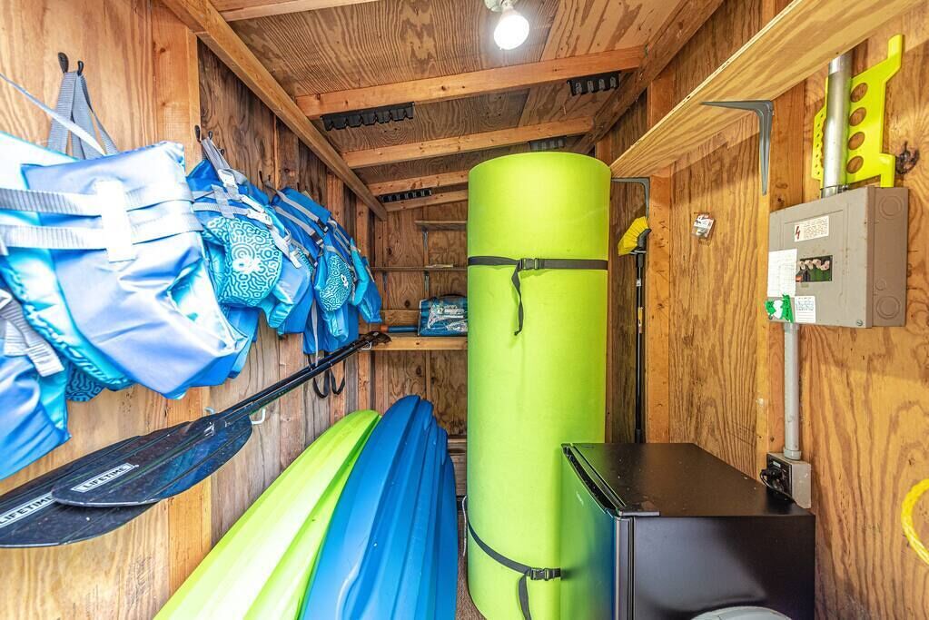 A wooden cabin interior with a sleeping area, a green cylindrical object, and a wall-mounted electrical box.