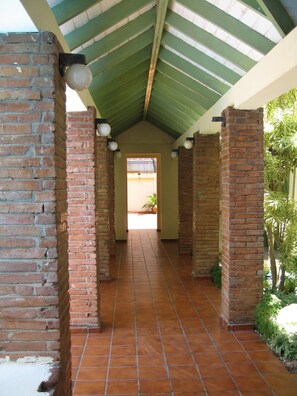 A covered brick corridor with a tiled floor and a green roof. - Cute 1BR in safe surroundings (Sosúa)
