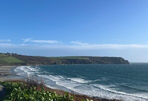 A coastal landscape with a clear sky, a sandy beach, and a cliff overlooking the ocean. - Gare Barn - Three Bedroom Cottage, Sleeps 6 (Ruan Lanihorne)