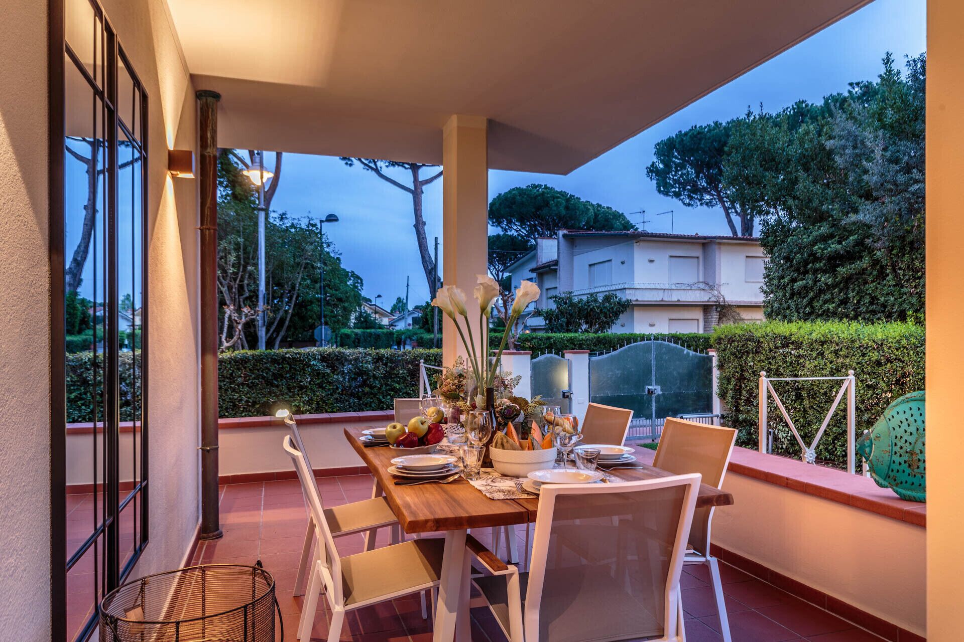 Un espace de restauration en plein air avec une table dressée pour quatre personnes, entourée de chaises, et offrant une vue sur un quartier résidentiel et des arbres en arrière-plan.