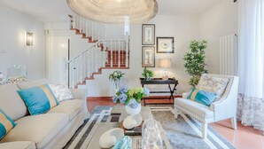 A spacious living room with a staircase, a large woven light fixture, and a coffee table with decorative items. - Regina Beach, Luxury 3 bedrooms Villa by the Beach in Marina di Pietrasanta (Marina di Pietrasanta)