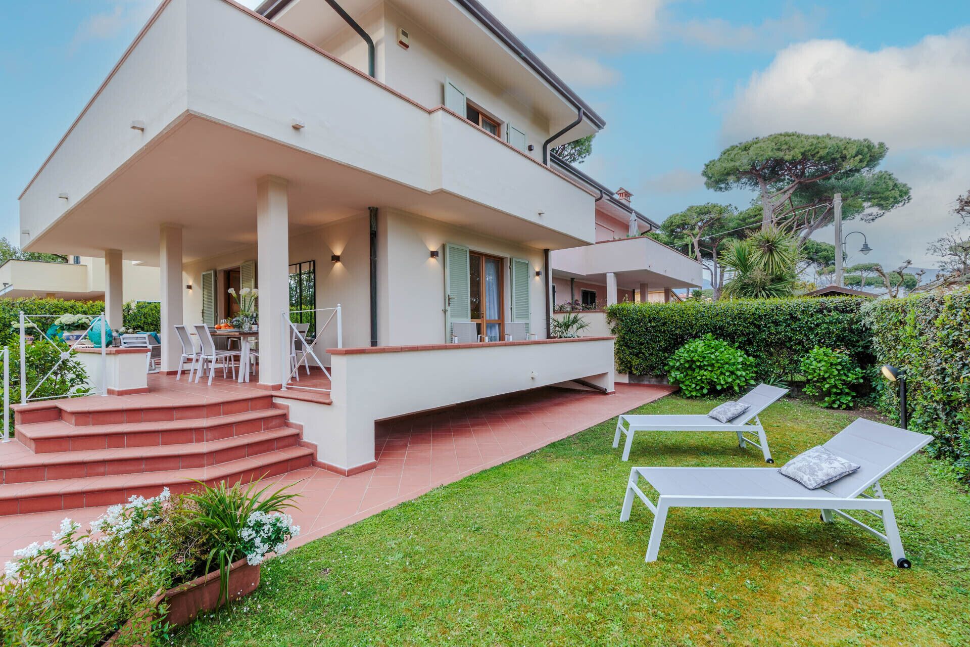 A two-story house with a covered patio, outdoor seating, and a well-maintained garden.
