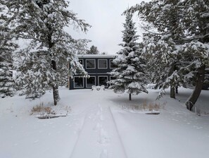 Surrounded by snow-covered trees, this two-story building offers a serene retreat.