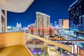 Ein Balkon mit Blick auf die nächtliche Stadtlandschaft, mit Hochhäusern und einem Casino.